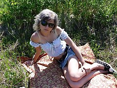 Gray-haired beauty posing naked outdoors on a blanket